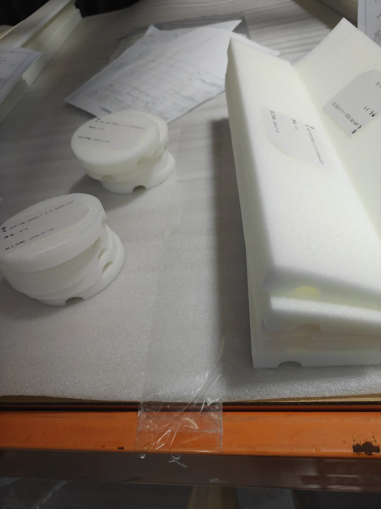 Machined white foam components beside a larger rectangular core block